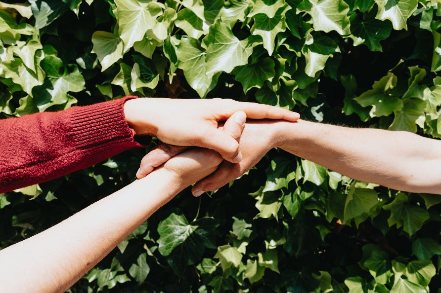 hand being held in front of green vines symbolizing united positive eco-friendly fashion